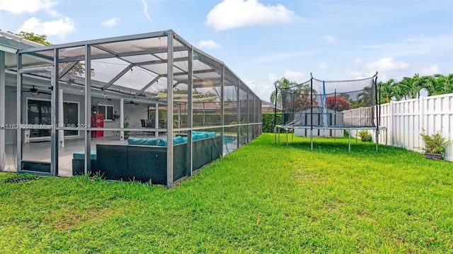 view of yard with a trampoline, a fenced in pool, glass enclosure, and a patio