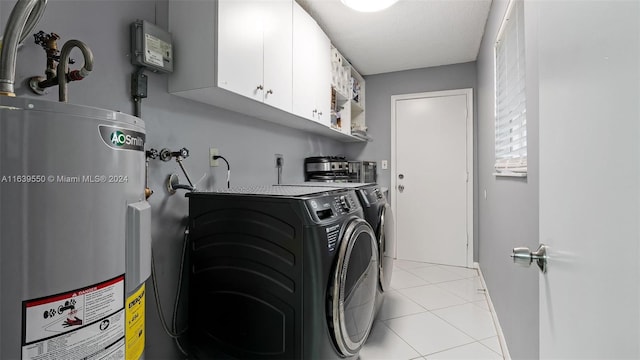 laundry area featuring a textured ceiling, cabinets, light tile patterned floors, water heater, and washing machine and dryer