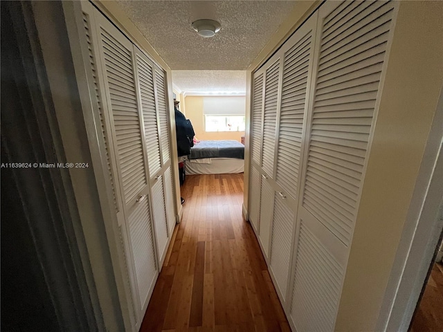 hallway with hardwood / wood-style floors and a textured ceiling