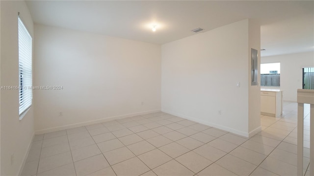 empty room featuring light tile patterned floors, visible vents, and baseboards