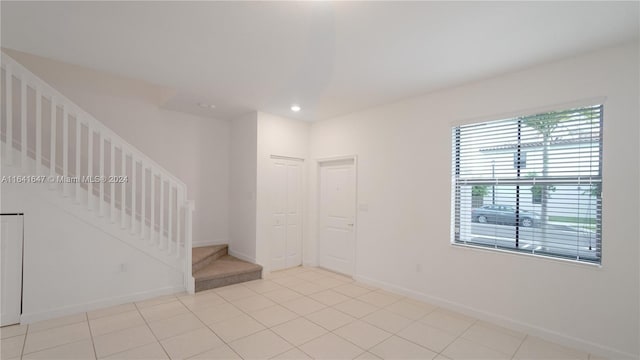 spare room featuring stairway, light tile patterned floors, recessed lighting, and baseboards