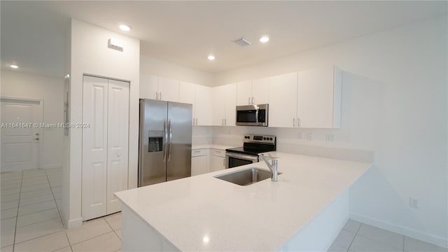 kitchen featuring visible vents, a peninsula, a sink, stainless steel appliances, and light countertops