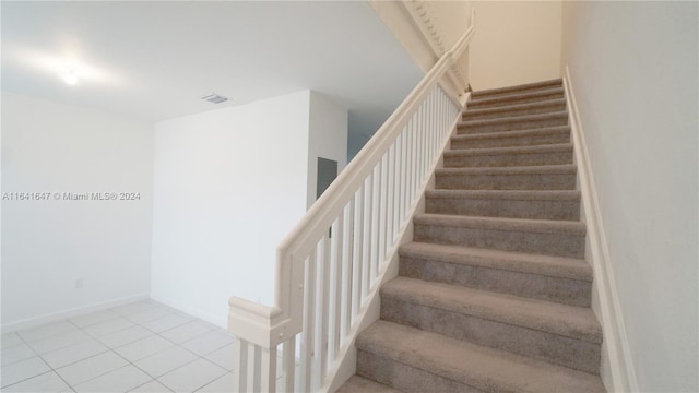 stairway featuring tile patterned flooring, baseboards, and visible vents