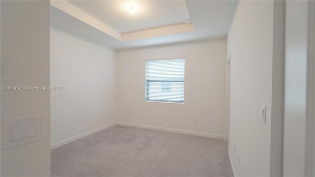 unfurnished room with baseboards, a tray ceiling, and carpet floors