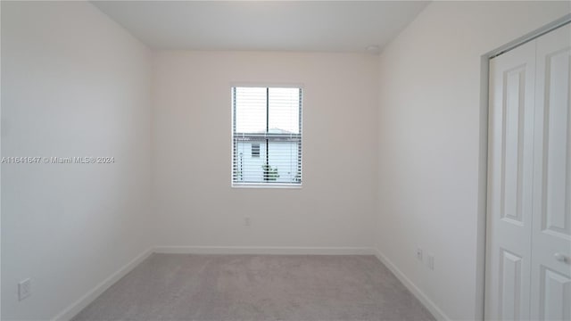 unfurnished room featuring baseboards and light carpet