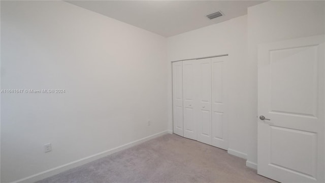 unfurnished bedroom featuring baseboards, visible vents, a closet, and light carpet