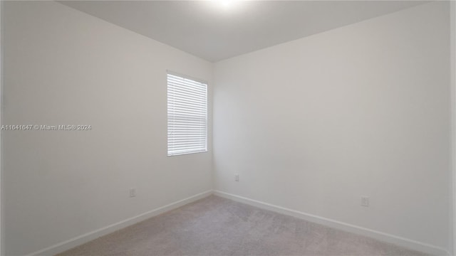 spare room with light colored carpet and baseboards