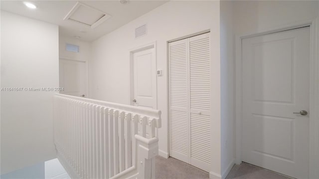 hallway with an upstairs landing, visible vents, recessed lighting, and attic access