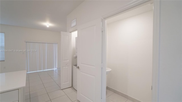 hall featuring light tile patterned floors, baseboards, and visible vents