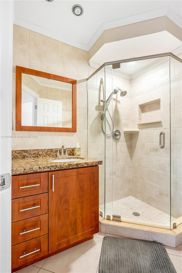 bathroom featuring tile walls, vanity, walk in shower, crown molding, and tile patterned flooring