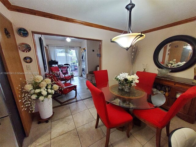 dining space with a textured ceiling, crown molding, stacked washer and clothes dryer, and light tile patterned floors