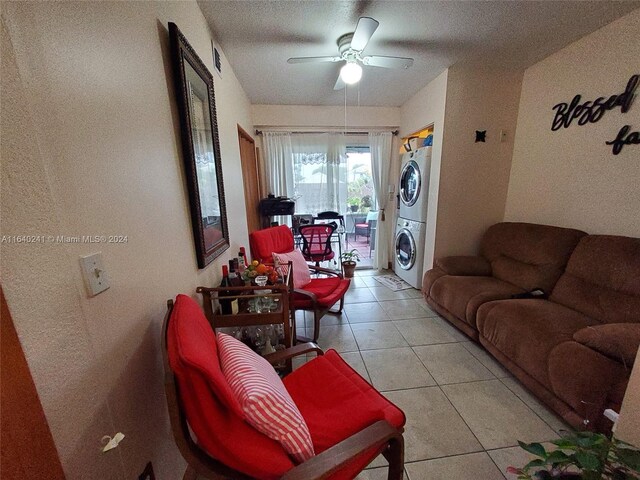 tiled living room with ceiling fan and stacked washer and dryer