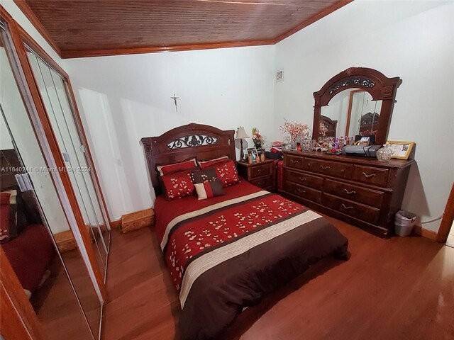 bedroom with a closet, crown molding, hardwood / wood-style floors, and wood ceiling