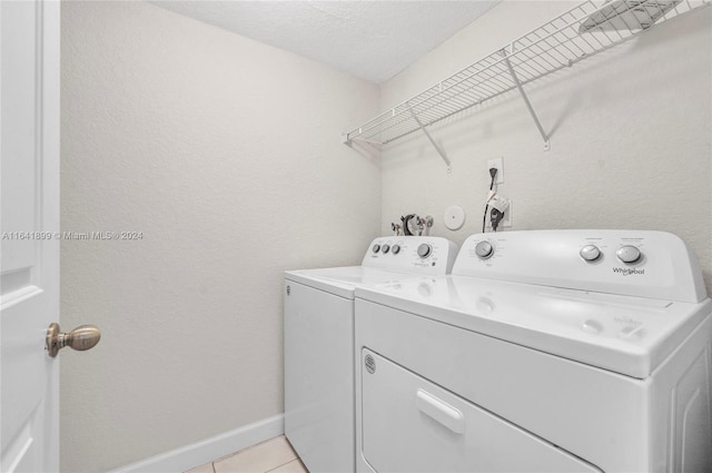 washroom featuring a textured ceiling, light tile patterned floors, and separate washer and dryer