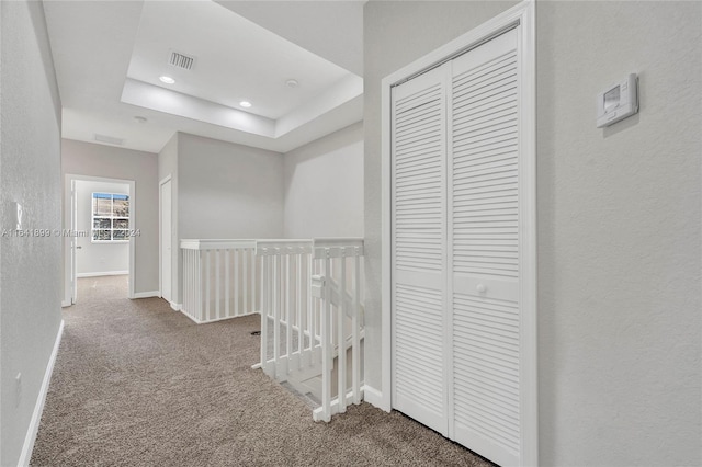 hallway with carpet flooring and a raised ceiling