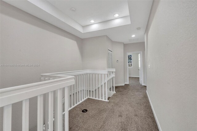 corridor featuring carpet and a raised ceiling