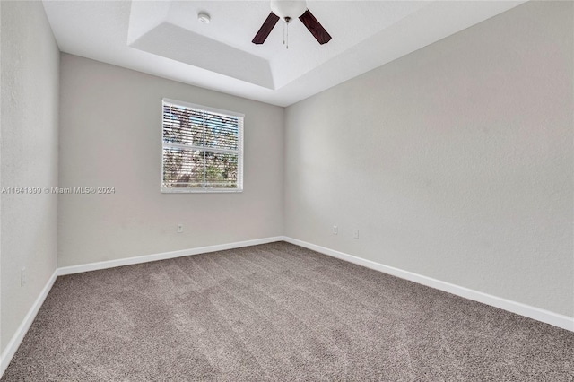 spare room featuring ceiling fan, a raised ceiling, and carpet