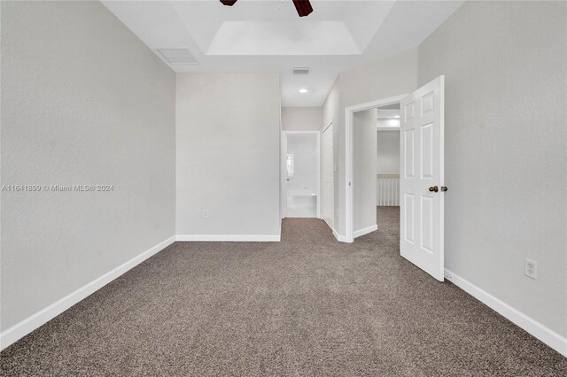 carpeted empty room with ceiling fan and a tray ceiling