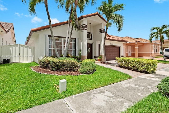 mediterranean / spanish-style home featuring a front lawn, a tiled roof, an attached garage, and stucco siding