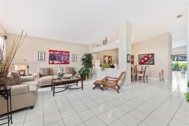 living room featuring lofted ceiling, light tile patterned flooring, visible vents, and baseboards