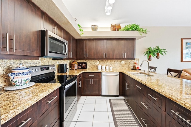 kitchen with light stone counters, light tile patterned floors, stainless steel appliances, decorative backsplash, and a sink