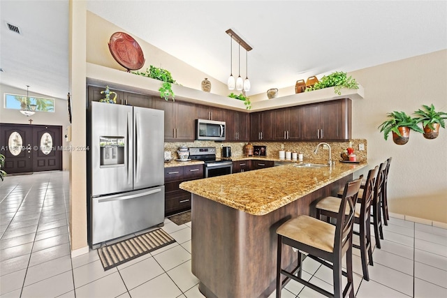 9045 NW 147th Ter, Miami Lakes, FL 33018 - kitchen featuring appliances with stainless steel finishes, vaulted ceiling, a peninsula, dark brown cabinets, and light stone countertops