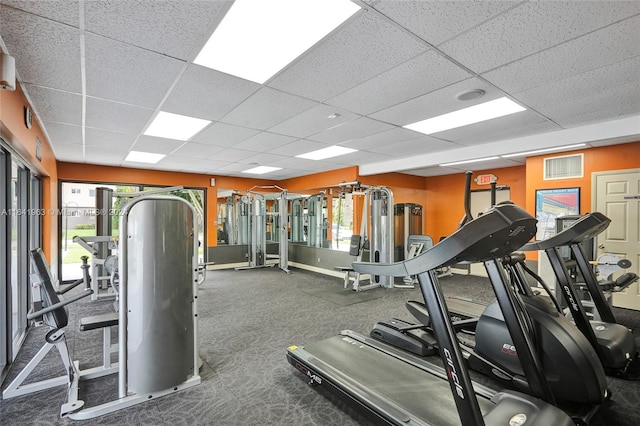 gym with a drop ceiling and carpet