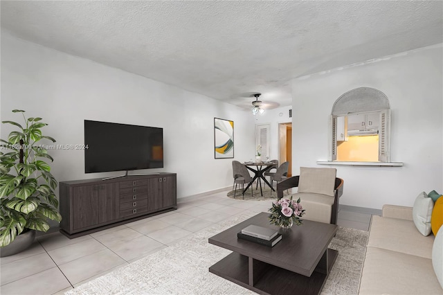 living room featuring ceiling fan, a textured ceiling, and light tile patterned floors