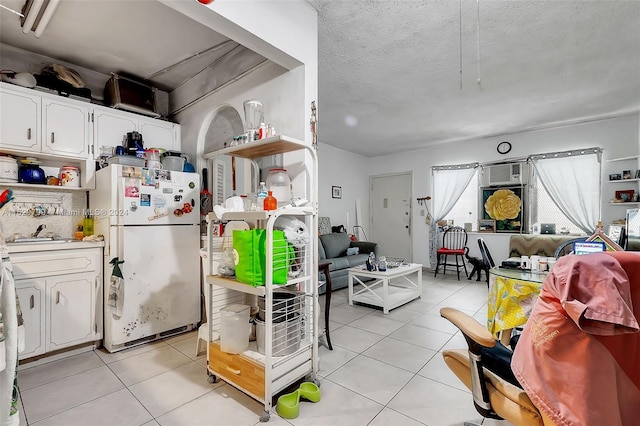 kitchen featuring a textured ceiling, white cabinets, light tile patterned floors, and white refrigerator