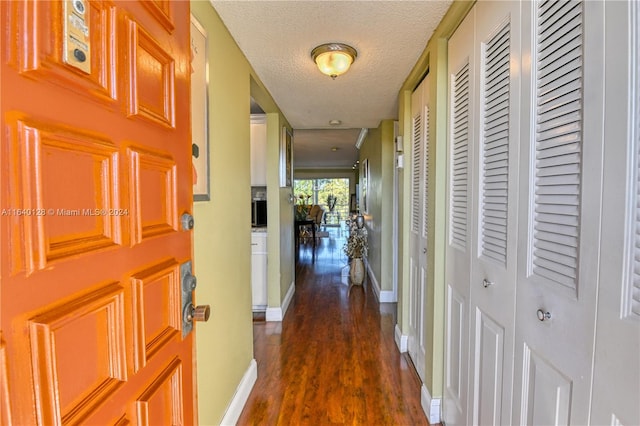 hall featuring dark wood-type flooring and a textured ceiling