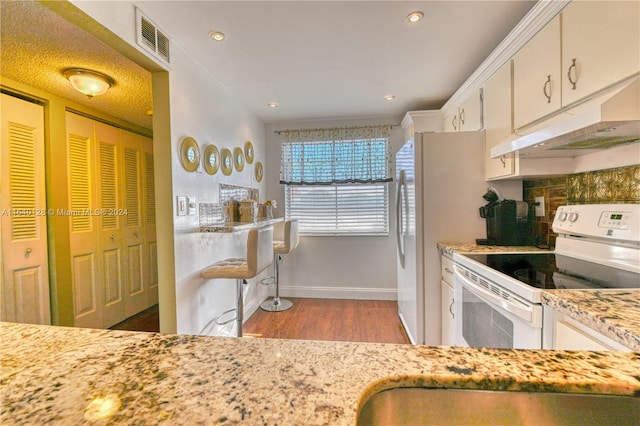 kitchen with premium range hood, white cabinets, light hardwood / wood-style flooring, white electric range oven, and light stone counters