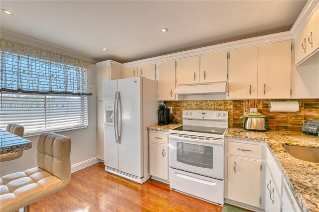 kitchen featuring tasteful backsplash, white cabinets, light wood-type flooring, and white appliances