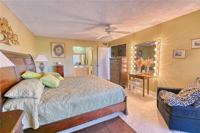 bedroom featuring ceiling fan, a textured ceiling, carpet floors, and connected bathroom