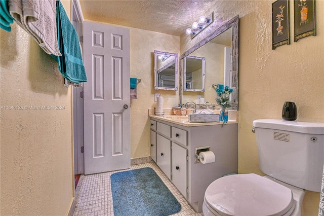 bathroom with tile patterned floors, a textured ceiling, vanity, and toilet