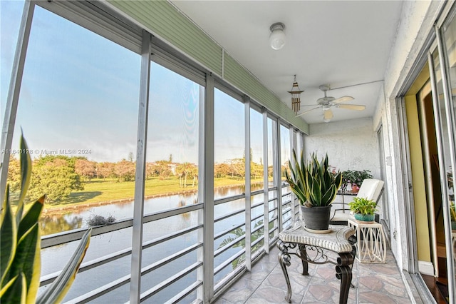 sunroom / solarium with ceiling fan and a water view