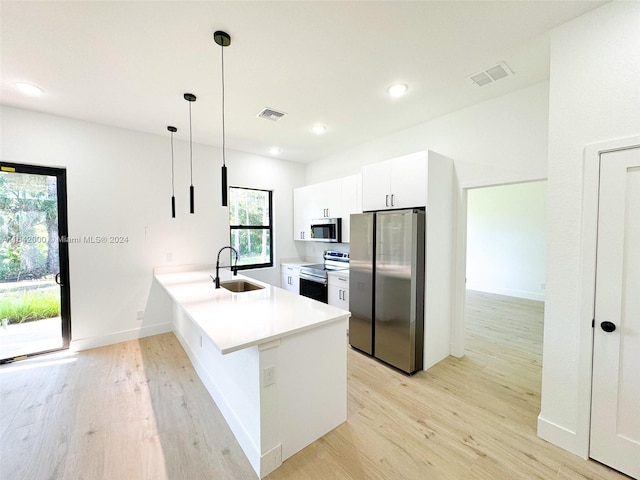 kitchen with sink, kitchen peninsula, decorative light fixtures, white cabinetry, and appliances with stainless steel finishes