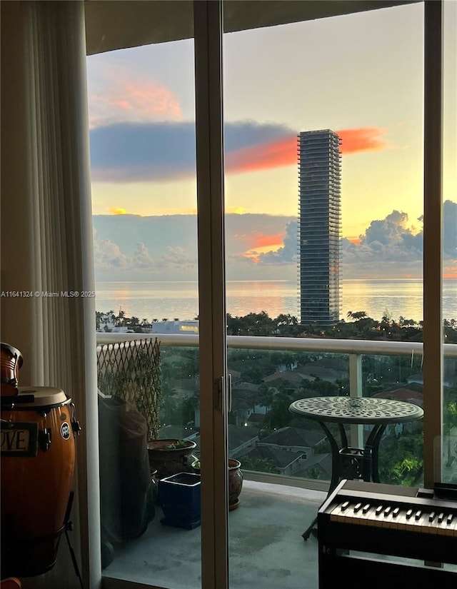 balcony at dusk featuring a water view