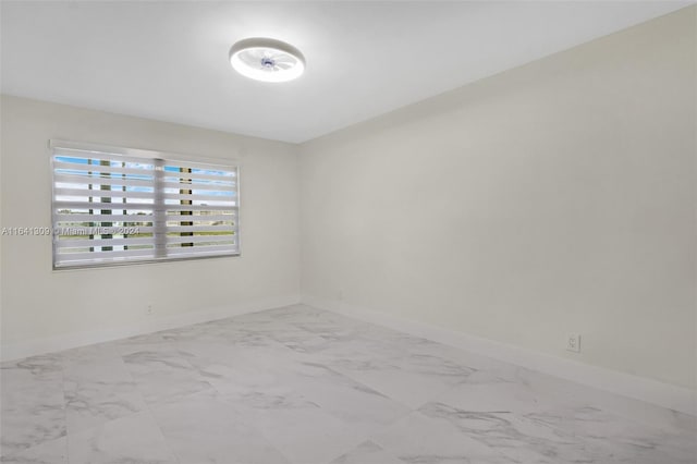 empty room featuring marble finish floor and baseboards