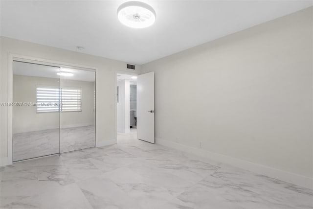 unfurnished bedroom with a closet, marble finish floor, visible vents, and baseboards