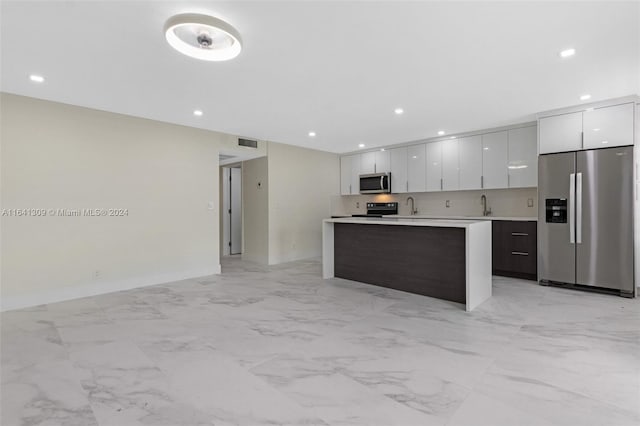 kitchen featuring appliances with stainless steel finishes, sink, light tile patterned floors, and a center island