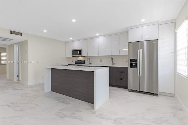 kitchen featuring marble finish floor, modern cabinets, appliances with stainless steel finishes, and a sink