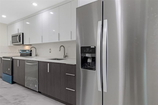 kitchen with light tile patterned floors, appliances with stainless steel finishes, sink, white cabinetry, and dark brown cabinetry