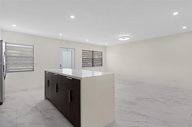 kitchen with dark brown cabinets, light tile patterned floors, a kitchen island, and stainless steel fridge with ice dispenser