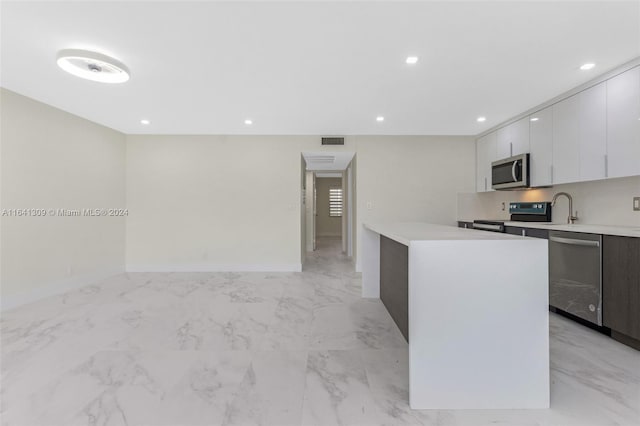 kitchen with light tile patterned floors, sink, stainless steel appliances, and white cabinetry