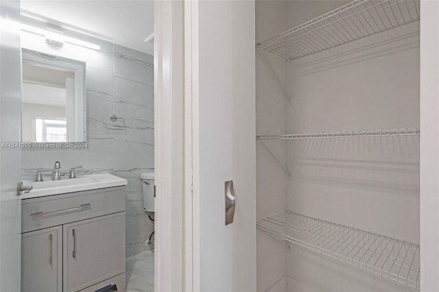 bathroom with tile walls, toilet, and vanity