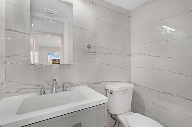 bathroom featuring tiled shower, tile walls, vanity, and toilet