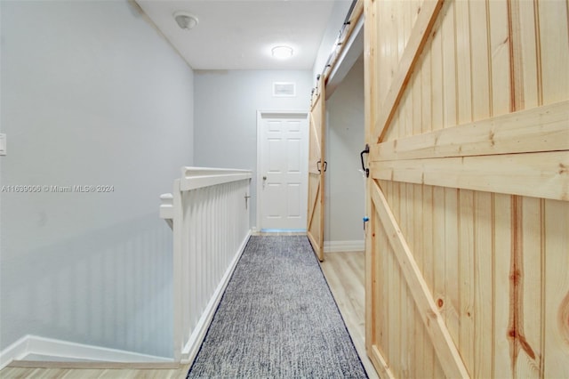 hall with light hardwood / wood-style floors and a barn door