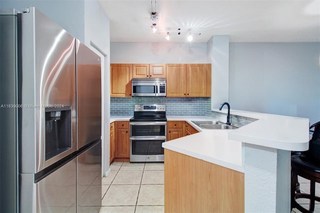 kitchen featuring light tile patterned flooring, sink, appliances with stainless steel finishes, decorative backsplash, and kitchen peninsula