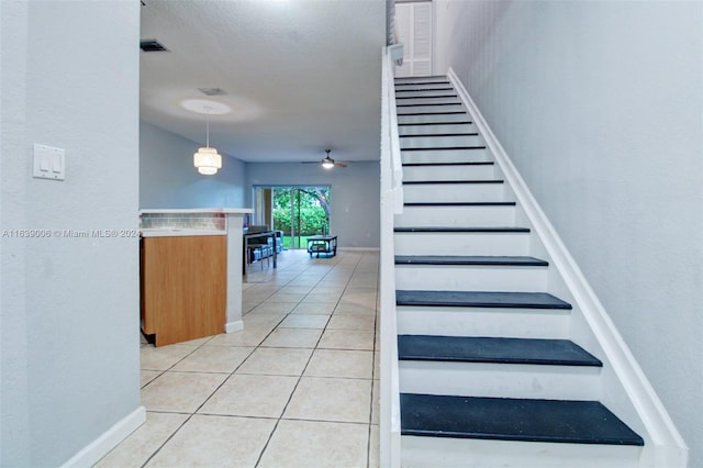 staircase featuring ceiling fan and tile patterned floors