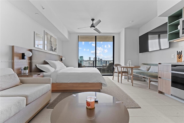 bedroom with ceiling fan, light tile patterned floors, expansive windows, and access to exterior